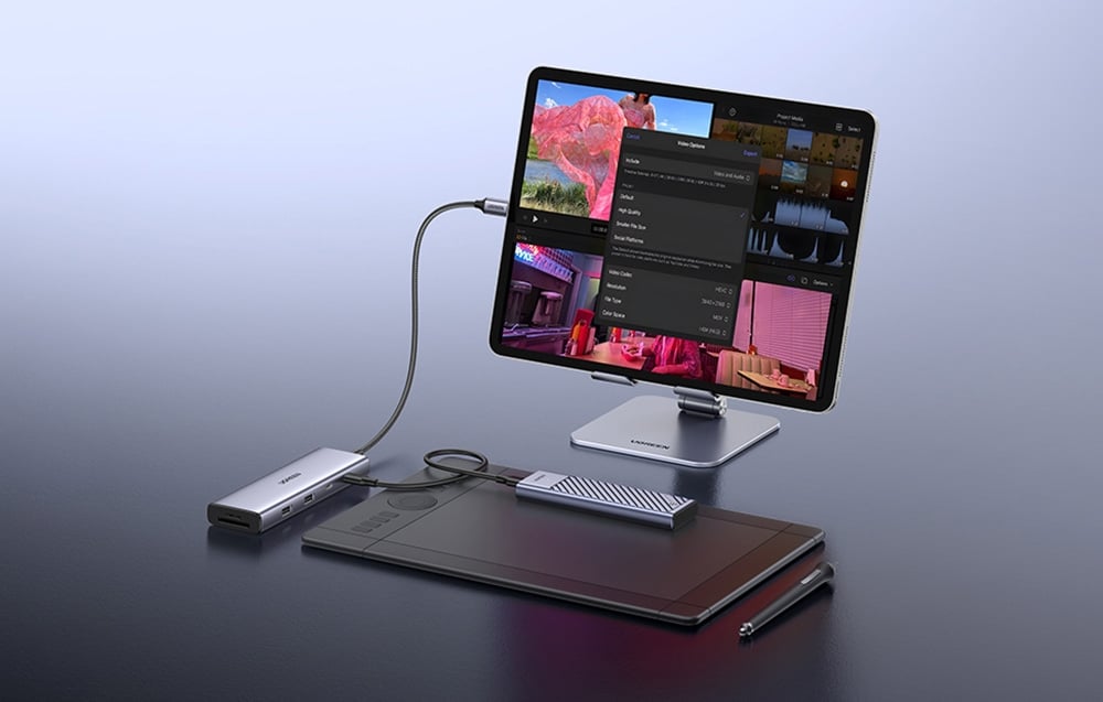 Hub UGREEN połączony z tabletem i zewnętrznymi akcesoriami graficznymi na biurku roboczym.