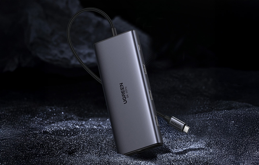 Hub UGREEN ustawiony pionowo na ciemnym tle z widocznym przewodem USB-C i bocznymi portami.