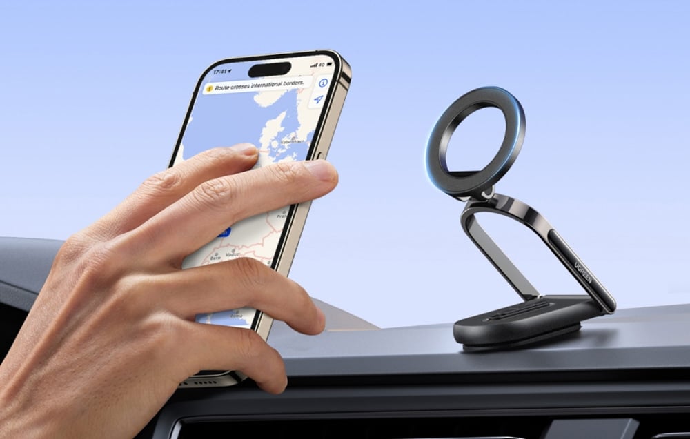 dłoń kierująca telefon z włączoną nawigacją do uchwytu magnetycznego