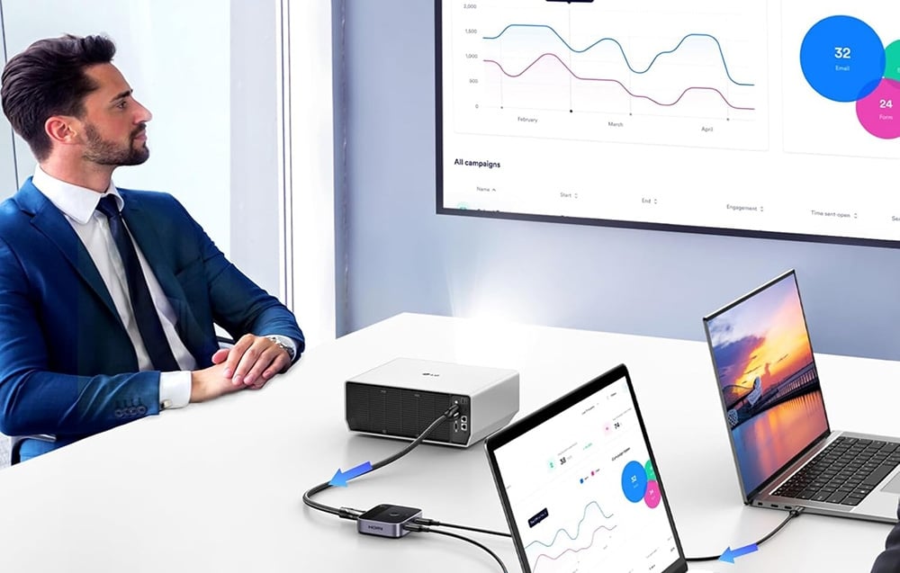 mężczyzna siedzący przed prezentacją wyświetlaną z laptopa na dużym ekranie