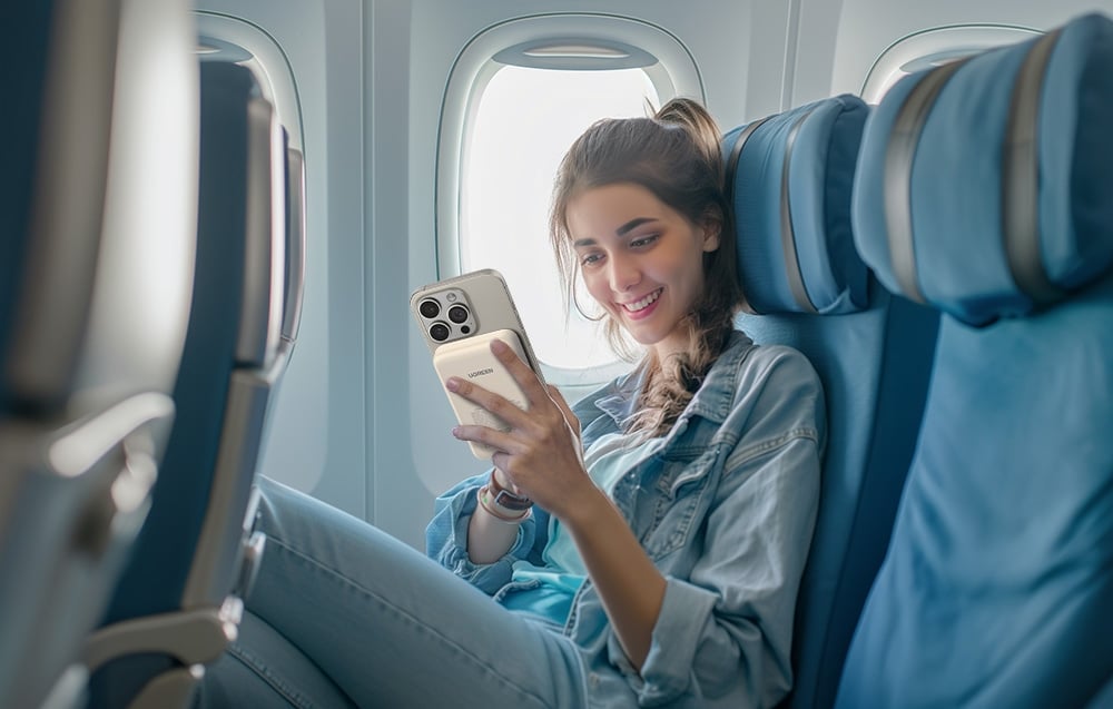 uśmiechnięta dziewczyna w samolocie z telefonem i powerbankiem magnetycznym 