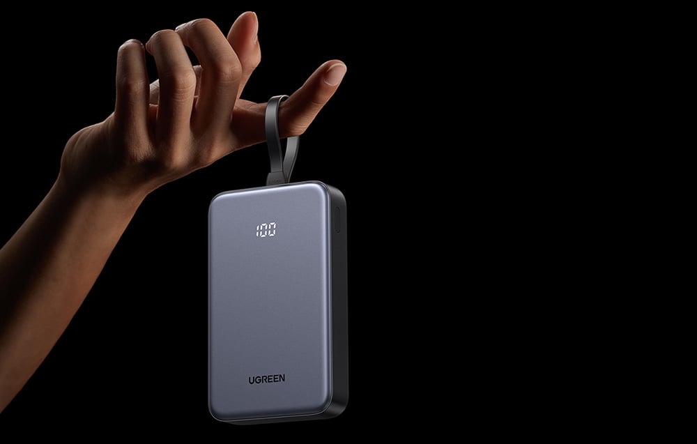szary powerbank ugreen zawieszony kablem na palcu dłoni