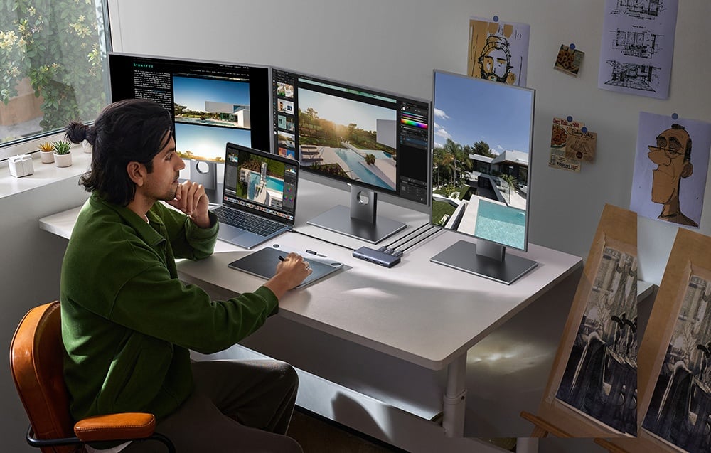 Mężczyzna pracujący przy biurku z laptopem i trzema monitorami podłączonymi przez hub UGREEN.