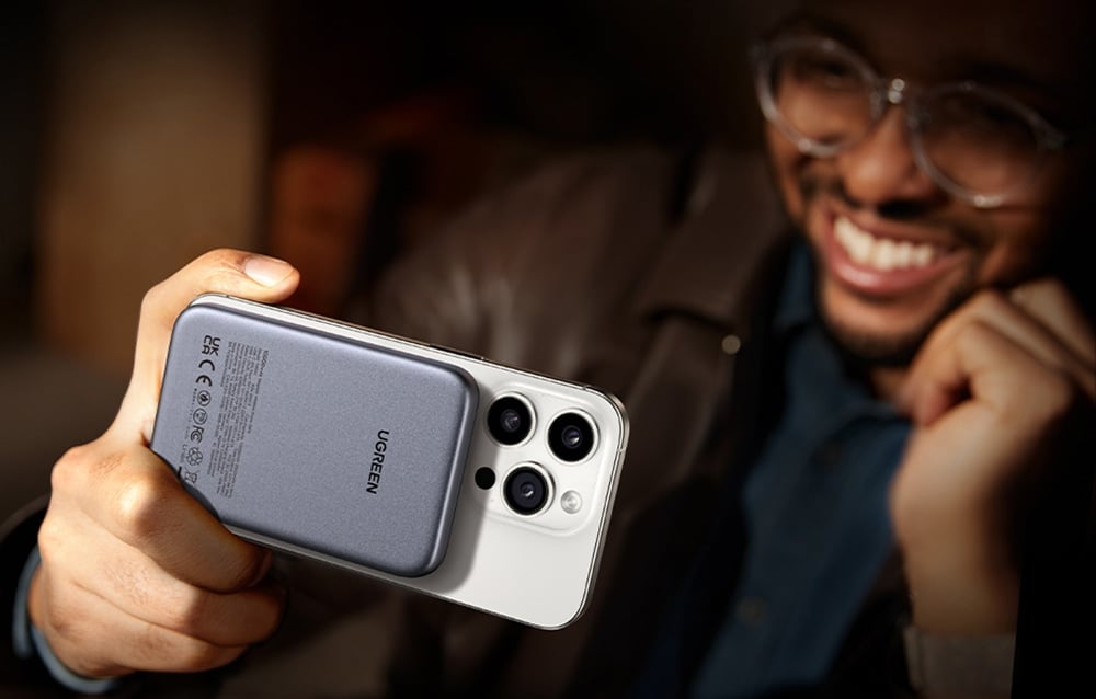 mężczyzna uśmiecha się do telefonu, który ładuje magnetyczny powerbank