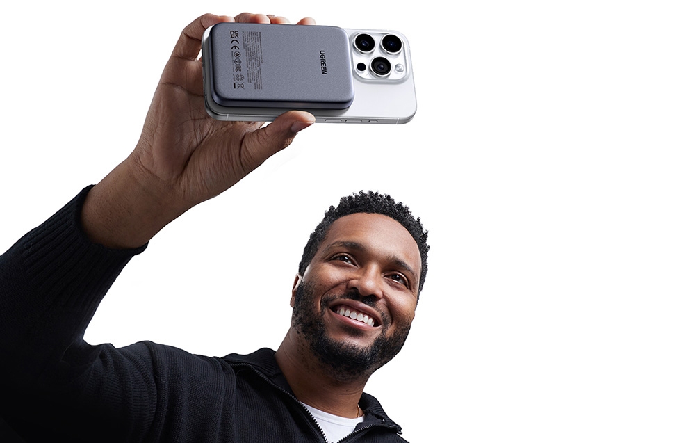 mężczyzna trzyma nad sobą telefon z powerbankiem magnetycznym