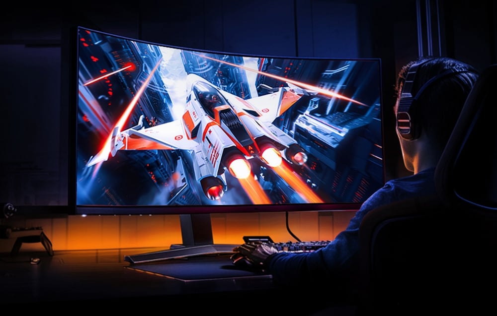 Osoba grająca w grę science-fiction na dużym zakrzywionym monitorze z dynamiczną grafiką myśliwca kosmicznego.