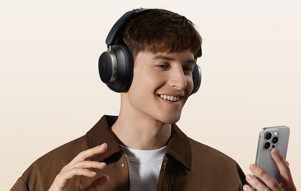 mężczyzna w słuchawkach nausznych uśmiecha się do telefonu