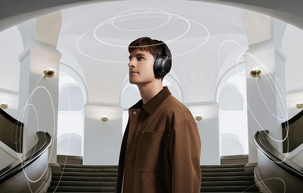 Mężczyzna w brązowej kurtce w słuchawkach nausznych stoi przed schodami