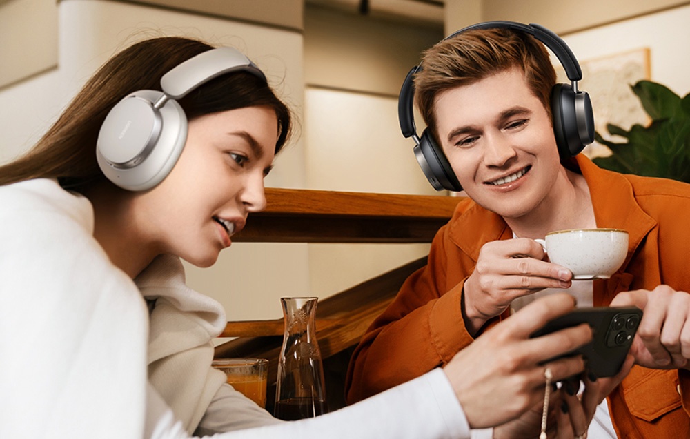 dziweczyna i chłopak patrzą razemw  ekran telefonu, majac na głowach słuchawki na uszne