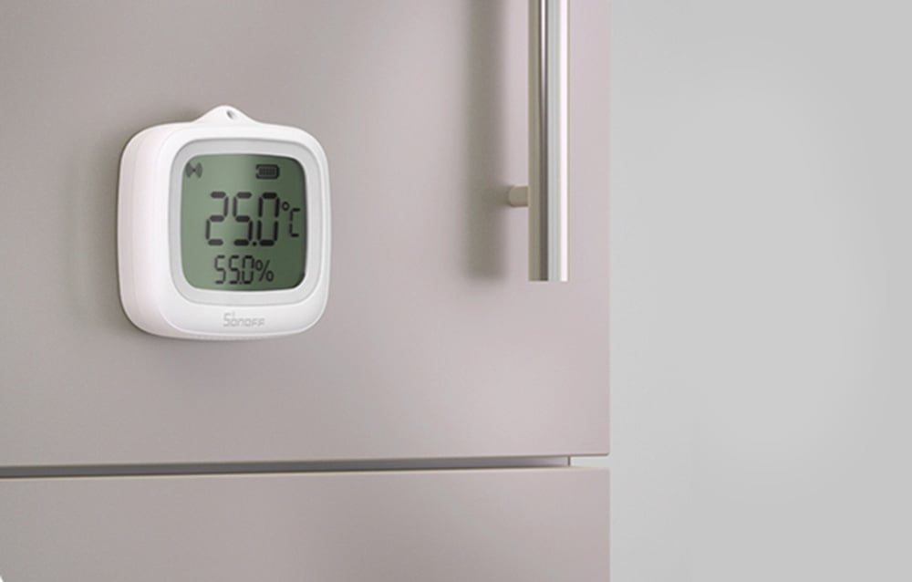 White digital thermometer-hygrometer showing 29.0°C and 55.0% humidity mounted on a refrigerator surface