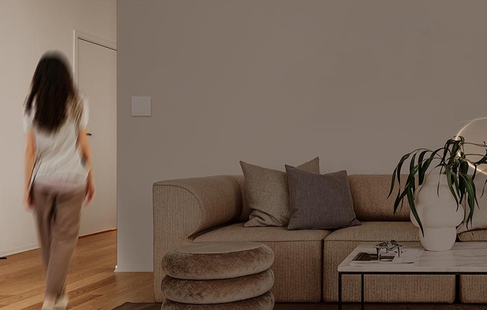 Kobieta w ruchu przechodzi przez nowoczesny salon z beżową sofą i drewnianą podłogą