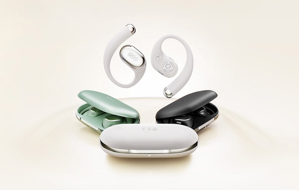 Białe słuchawki bezprzewodowe z zaczepiami za ucho unoszące się nad trzema kolorowymi etui ładującymi - zielonym, czarnym i białym.
