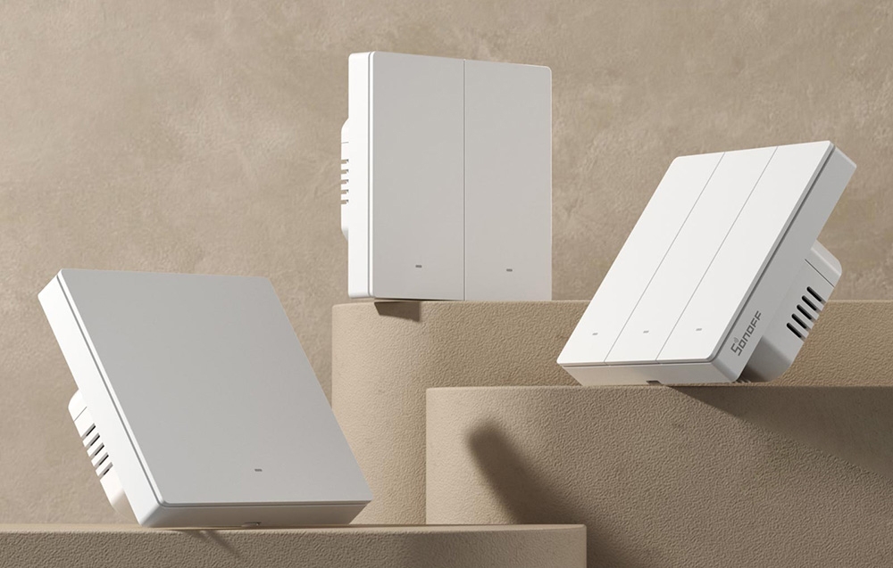 Trzy białe inteligentne przełączniki SONOFF różnych typów ułożone na beżowych geometrycznych blokach