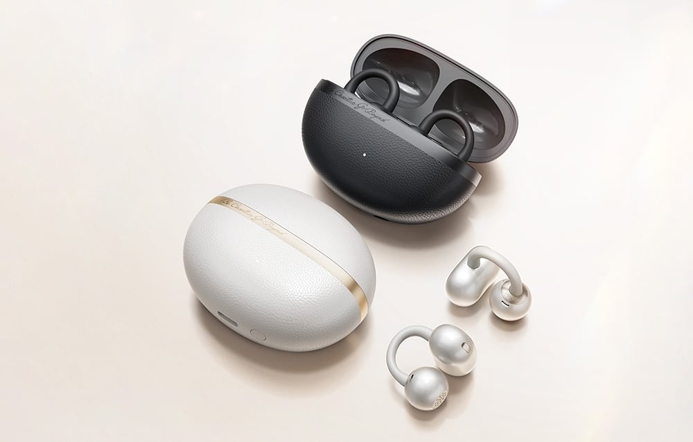 Dwie białe słuchawki bezprzewodowe z etui w kolorze białym i czarnym, leżące na jasnym tle