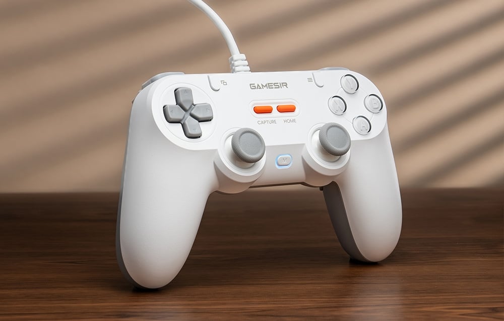 Biały kontroler GameSir stojący pionowo na drewnianym stole z oświetleniem w tle.