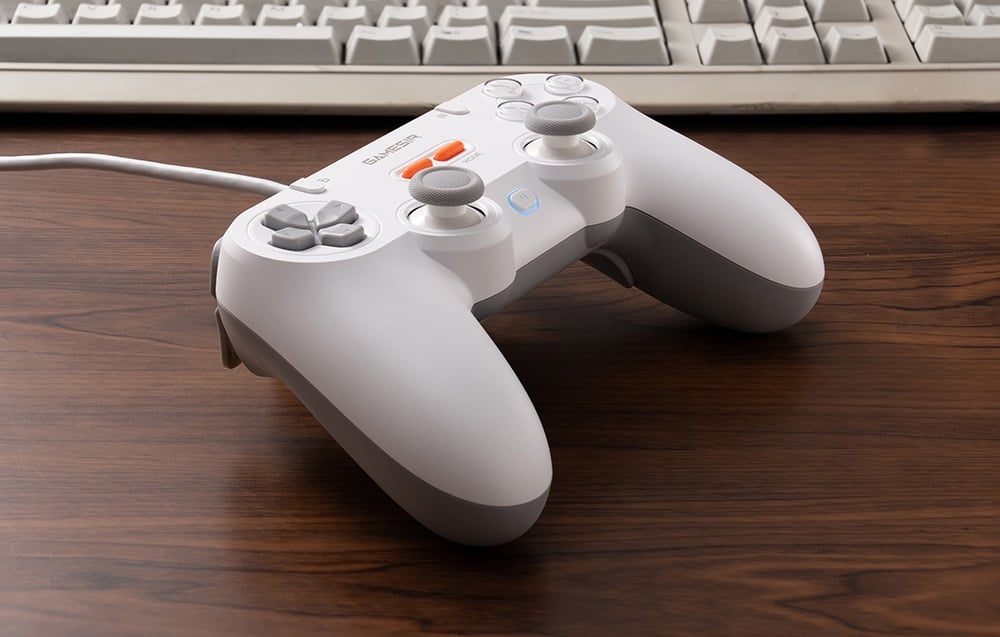 Biały kontroler GameSir leżący na blacie przed klasyczną klawiaturą komputerową.