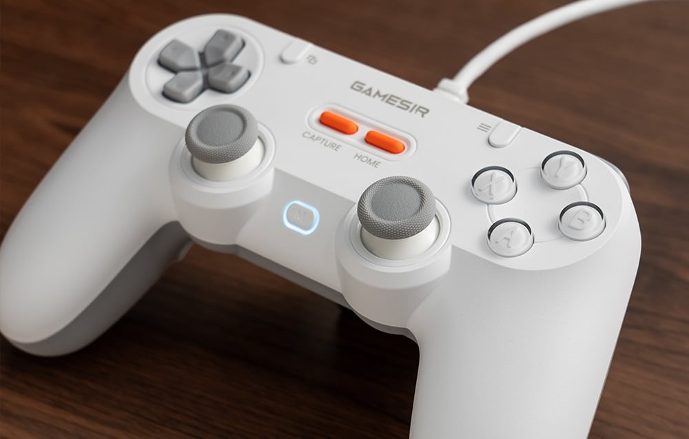 Zbliżenie na biały kontroler GameSir z widocznymi przyciskami i podświetlonym przyciskiem „M”.