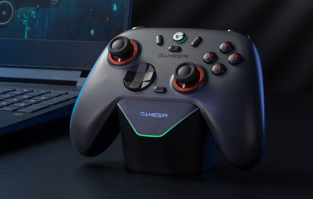 Ciemnoszary kontroler GameSir z czerwonym podświetleniem umieszczony na stacji dokującej przed laptopem.