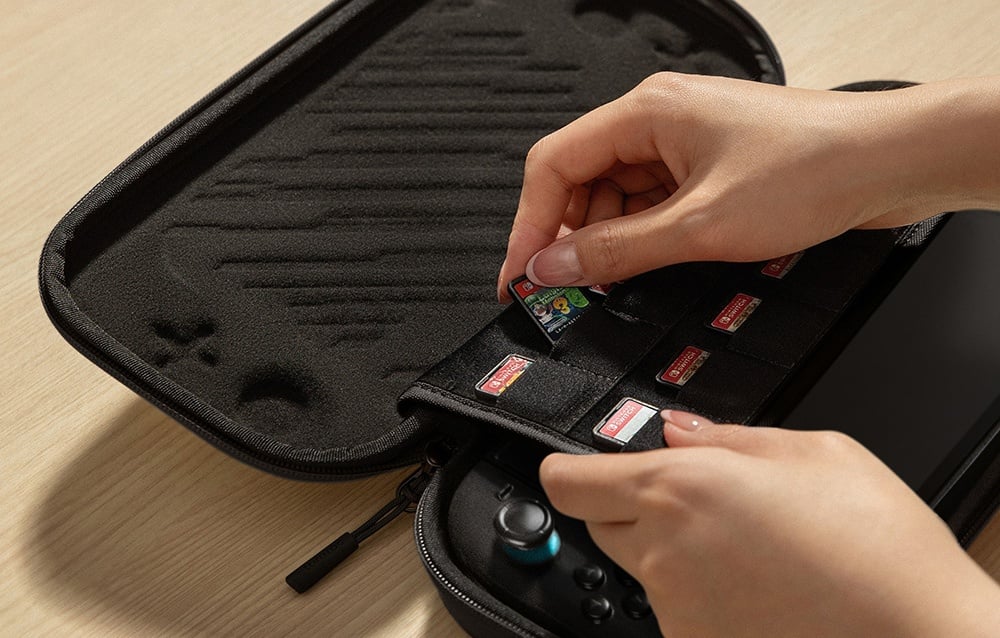 Ręce wkładające kartridże do gier Nintendo Switch do czarnego etui