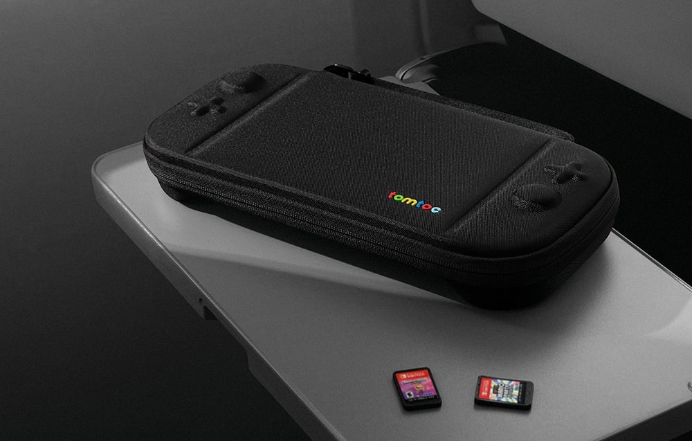 Czarne etui tomtoc z kolorowym logo na jasnej powierzchni obok dwóch kartridży do gier