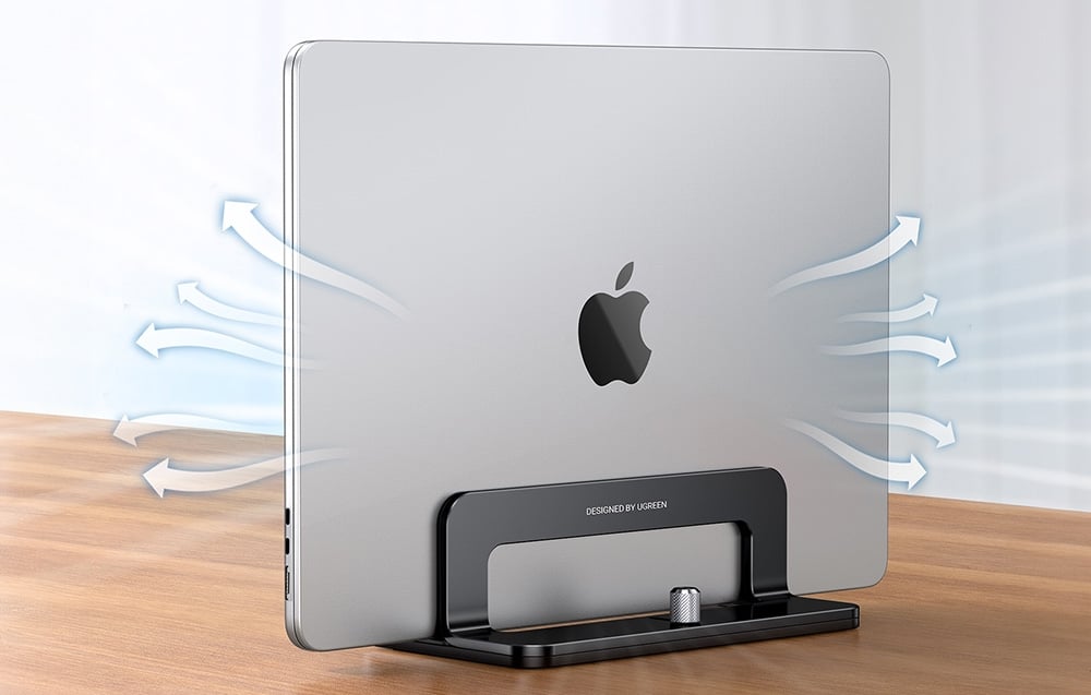 A MacBook in a black UGREEN stand with graphic arrows showing air circulation on a wooden desk