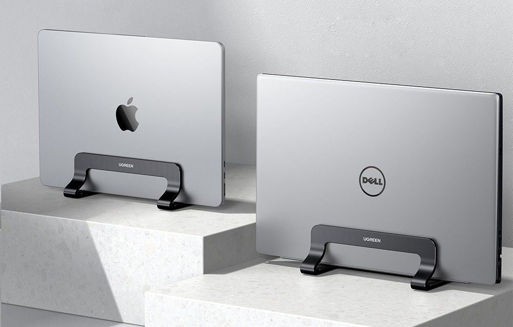 Two laptops - a MacBook and a Dell - in black stands on white shelves
