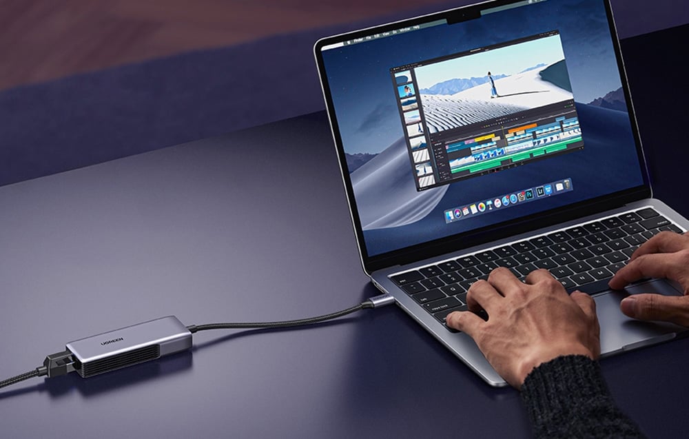 Hands on a MacBook keyboard connected to the adapter while editing video