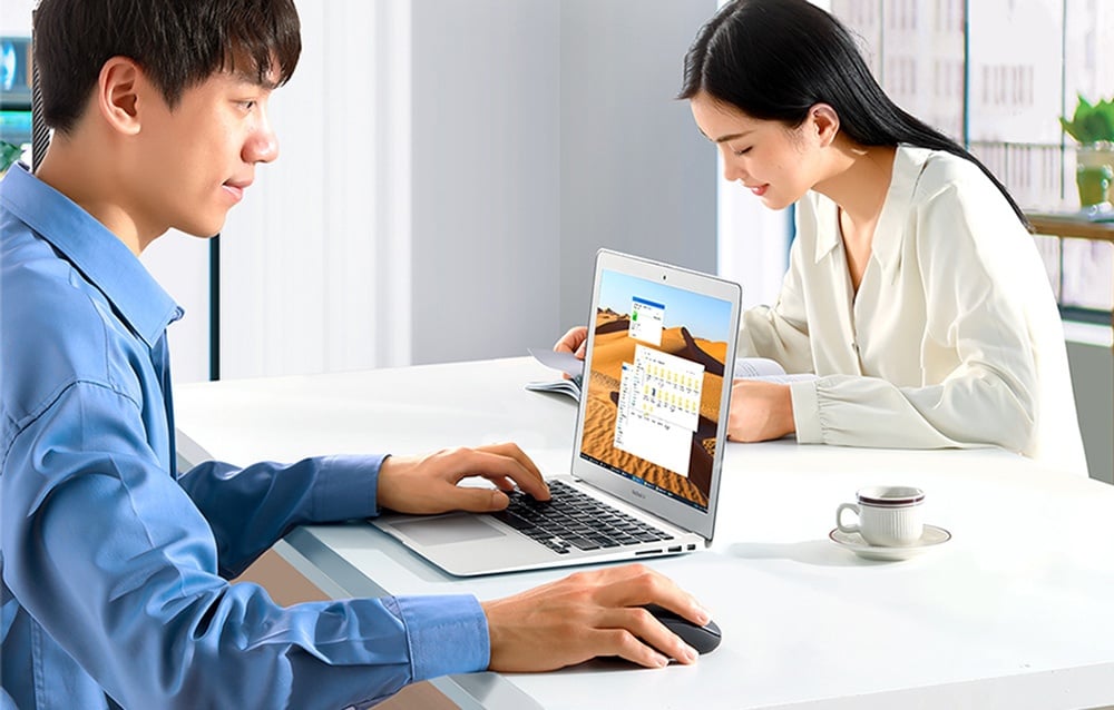 mężczyzna pracujący przy laptopie i kobieta czytająca książkę w jasnym pomieszczeniu