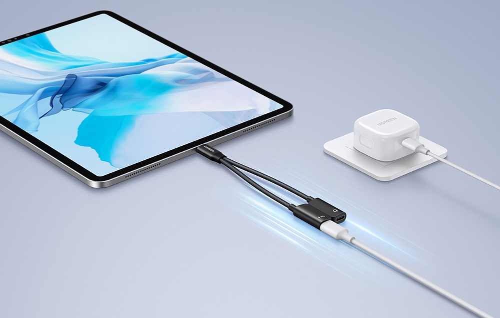 A tablet with a blue screen connected by cable to a white charger on a gray background