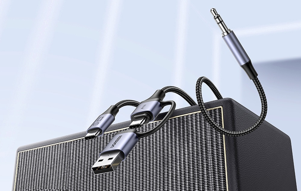 a black cable with a 3.5 mm jack plug lies on a speaker against a light background