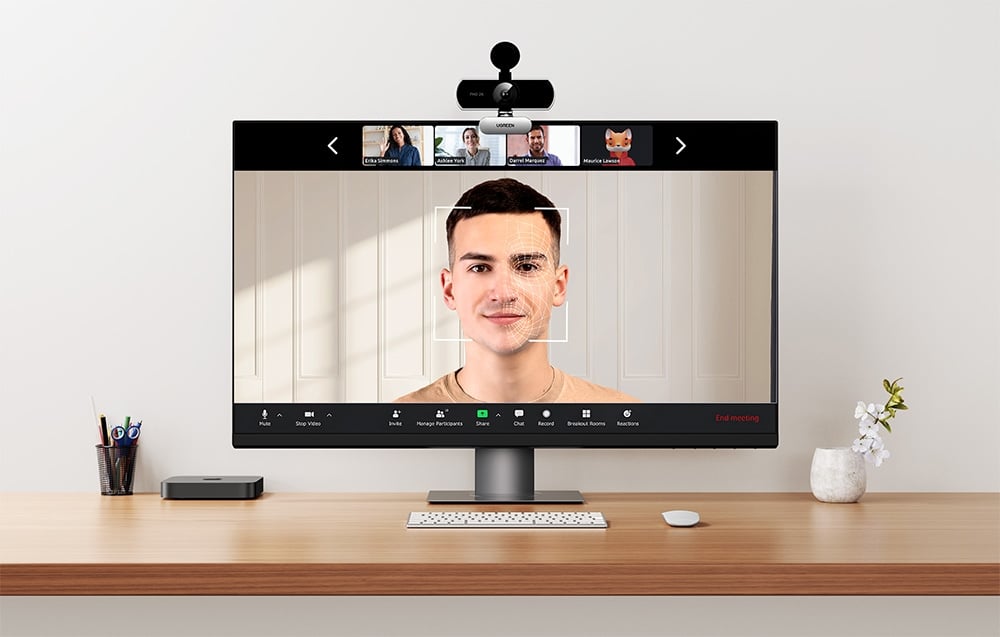 Monitor with a video conference showing a man in the main window and thumbnails of other participants with a camera on top, on the monitor webcam