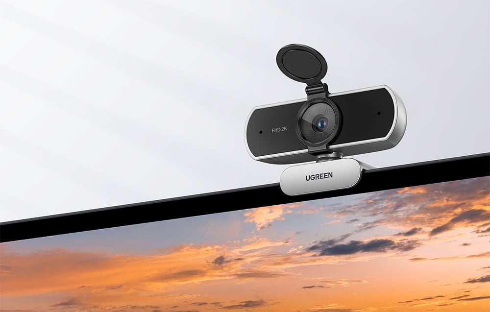 Black UGREEN webcam with a privacy cover attached to the edge of a monitor