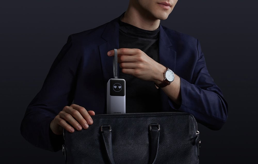 Mężczyzna chowa powerbank Ugreen do torby za pomocą paska