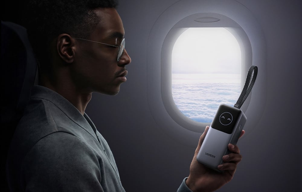 Mężczyzna trzymający powerbank Ugreen przy oknie samolotu