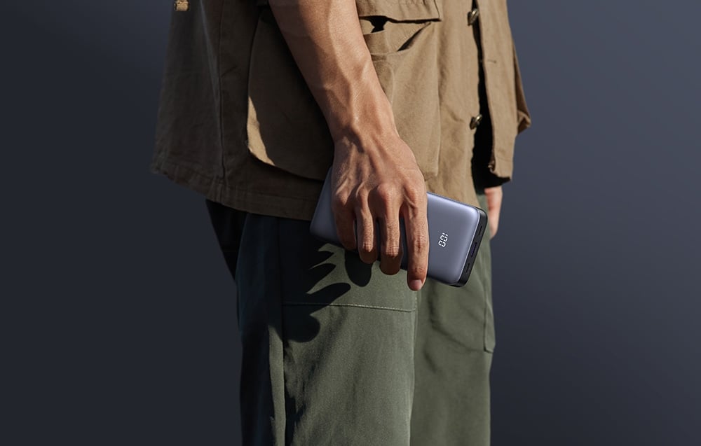 Mężczyzna trzymający w ręce powerbank UGREEN na tle ciemnego tła w plenerze