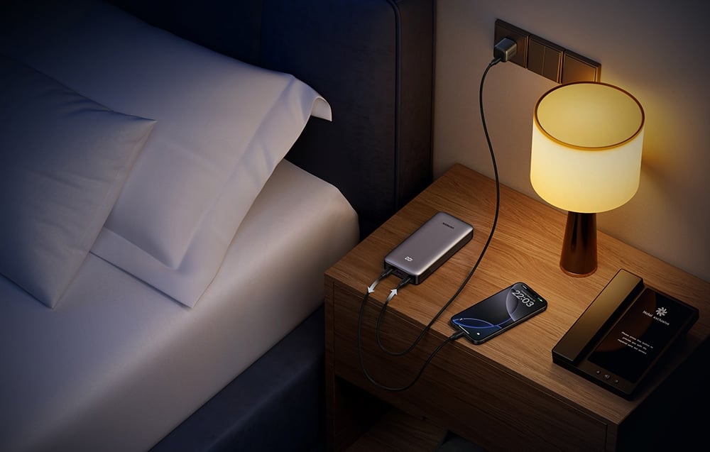 Powerbank UGREEN ładujący telefon na stoliku nocnym obok łóżka i lampki
