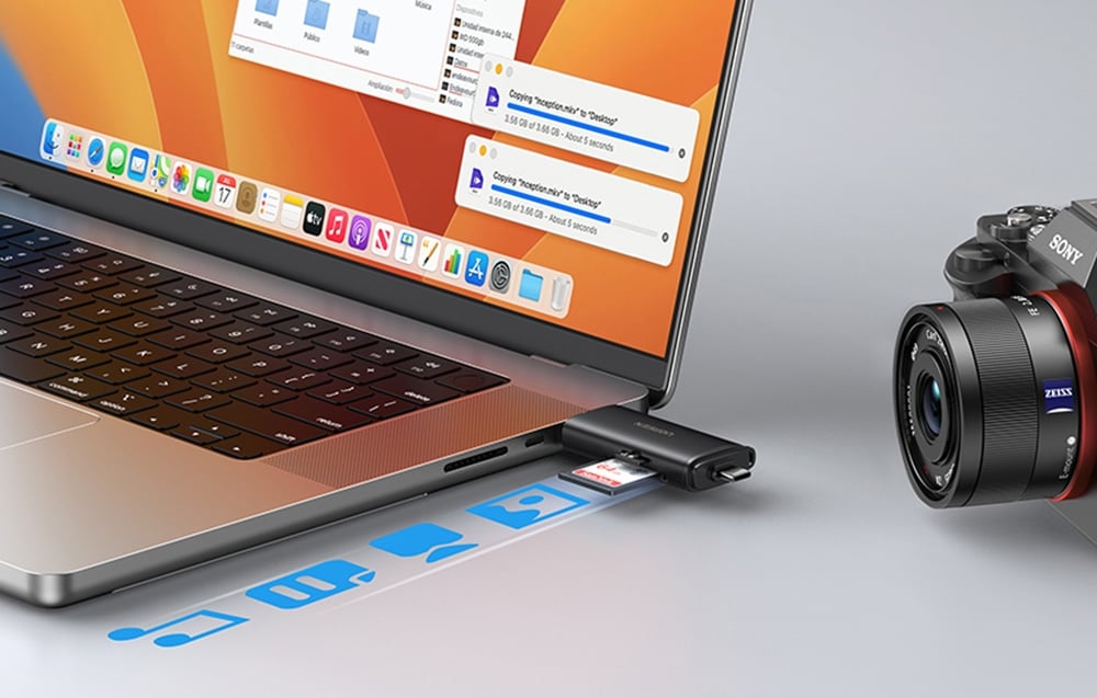 Laptop with an orange wallpaper connected to a black UGREEN adapter next to a camera on a desk