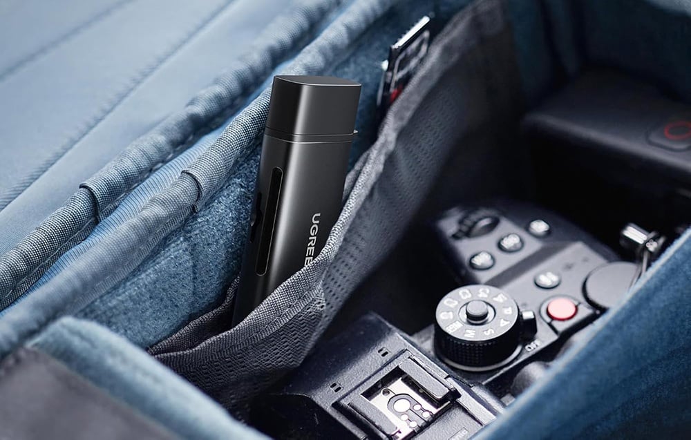 black memory card reader lying in a backpack pocket next to photography equipment