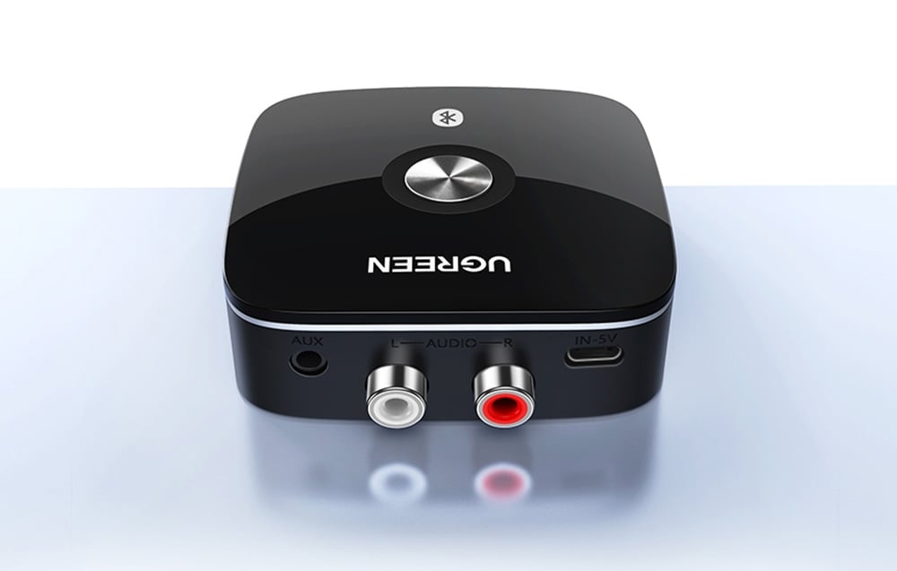 Czarny adapter audio Bluetooth UGREEN z portami RCA i AUX na białym tle z odbiciem