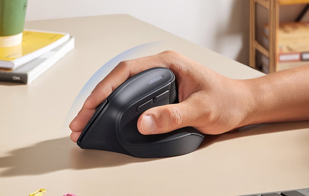 Czarna ergonomiczna myszka UGREEN trzymana w dłoni na biurku