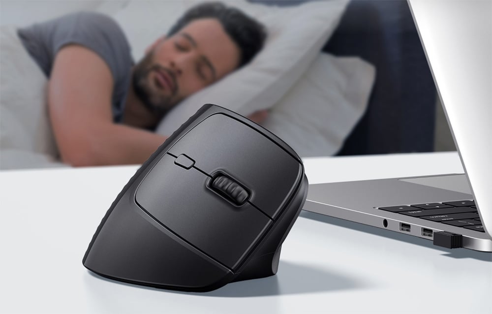 Czarna myszka UGREEN stojąca obok laptopa ne tle przedstawiającym śpiącego mężczyznę