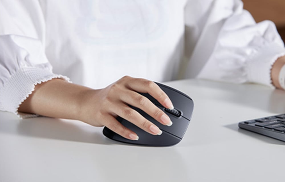 Dłoń kobiety pracującej przy komputerze z klasyczną czarną myszką UGREEN