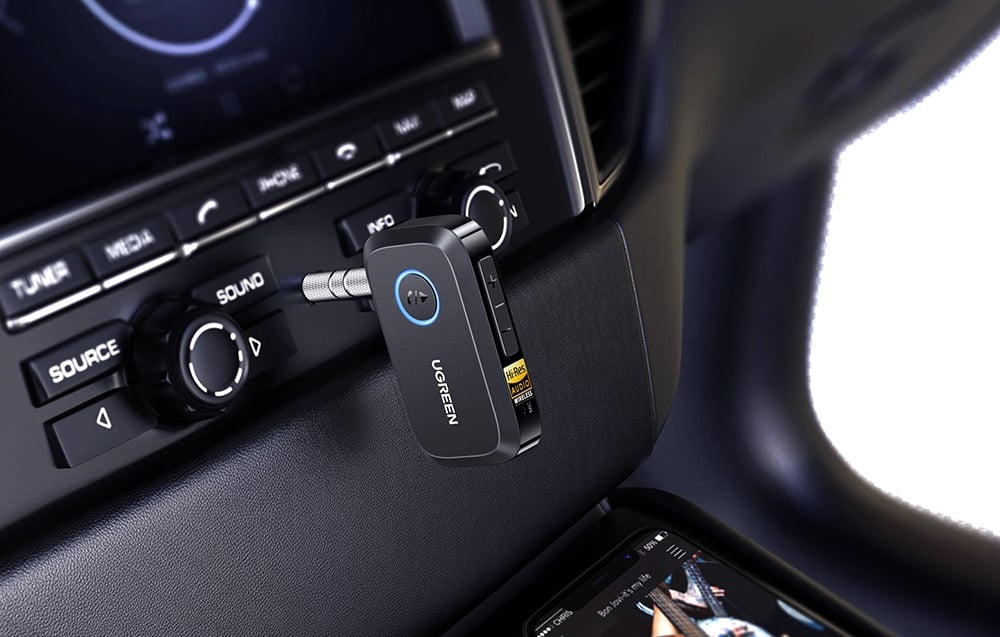 Czarny adapter Bluetooth UGREEN podłączony do radia samochodowego w kokpicie pojazdu