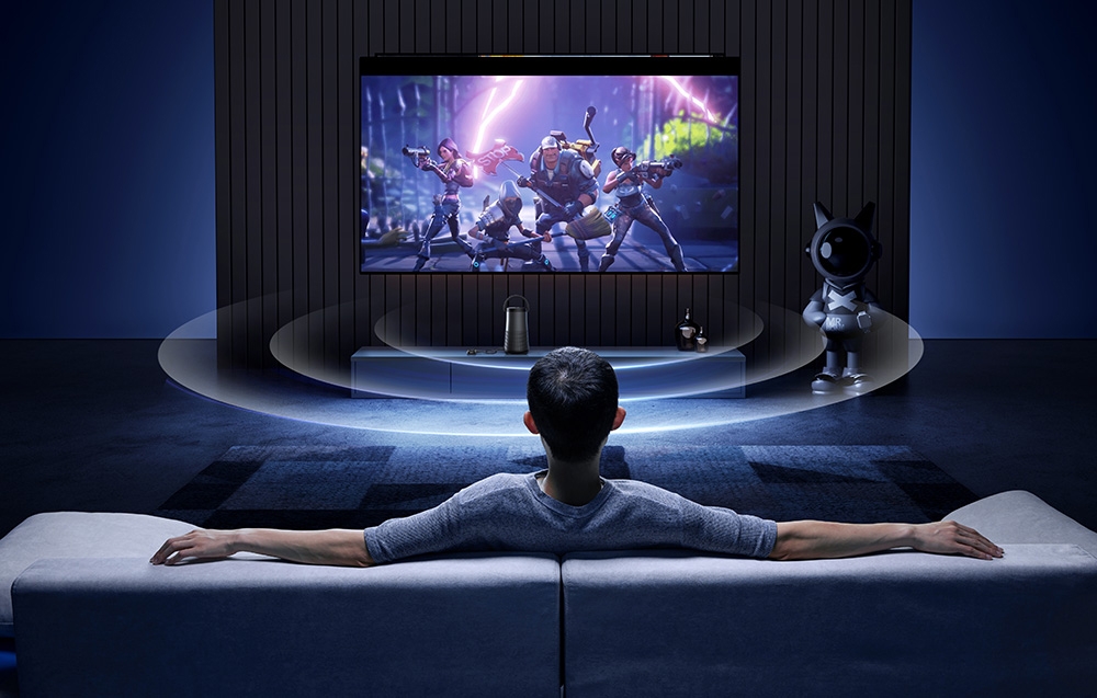Mężczyzna siedzi na kanapie oglądając grę na dużym ekranie w nowoczesnym salonie z robotem