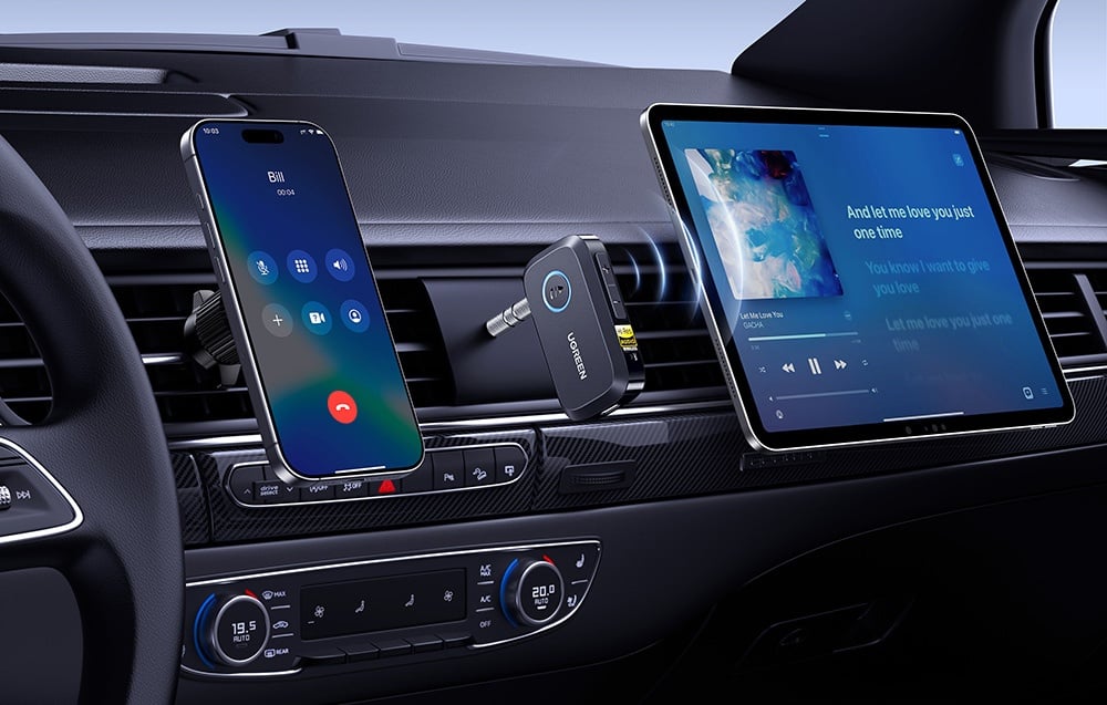 Wnętrze samochodu z telefonem w trybie rozmowy i tabletem z muzyką podłączonymi do adaptera