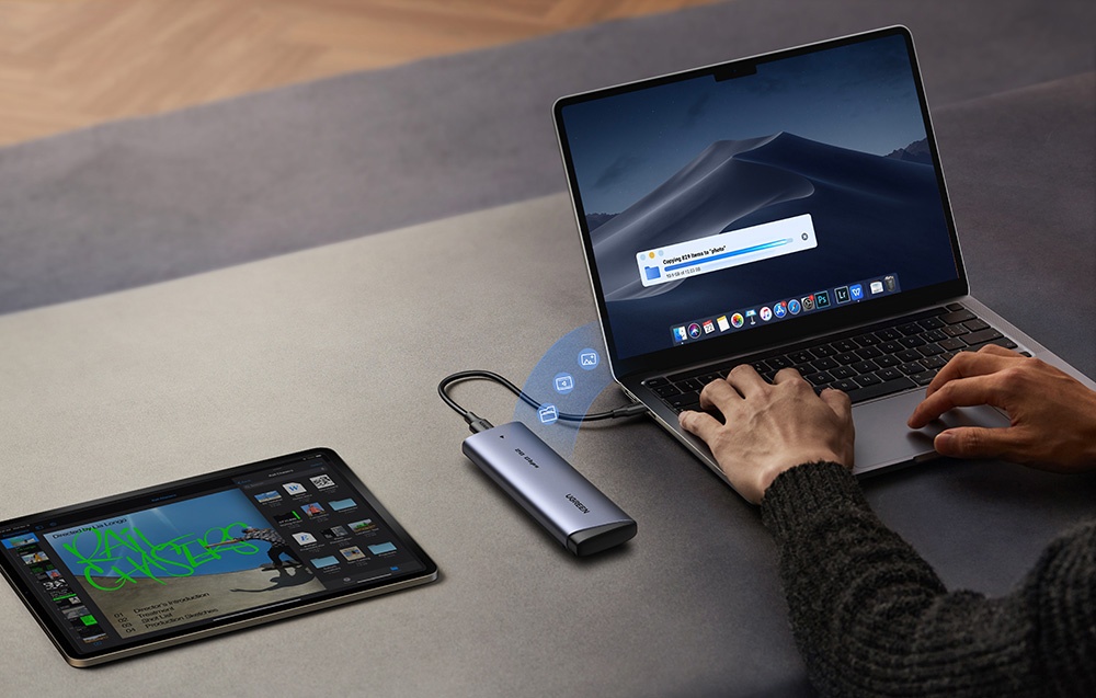 UGREEN SSD connected to a laptop transferring files, next to a tablet with an open app