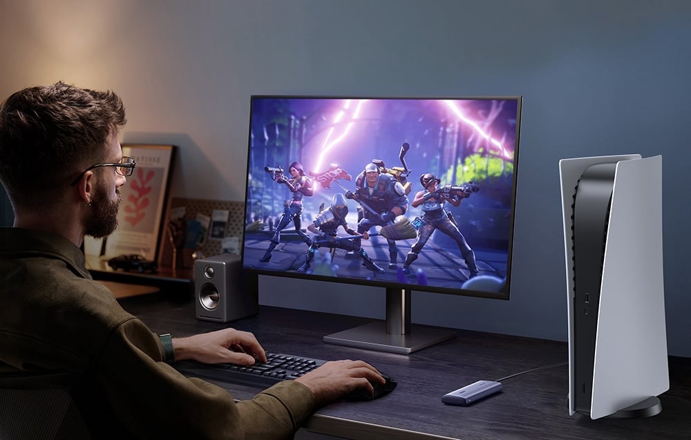 A gamer using a PlayStation console and monitor with an UGREEN SSD connected