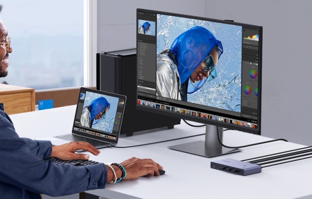 mężczyzna w okularach edytuje zdjęcie na monitorze podłączonym do laptopa