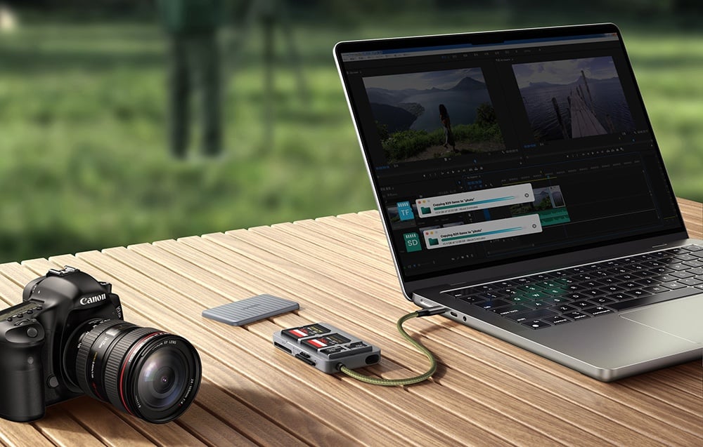 Laptop auf dem Tisch mit geöffnetem Videobearbeitungsprogramm ist an den Kartenleser neben der Kamera angeschlossen