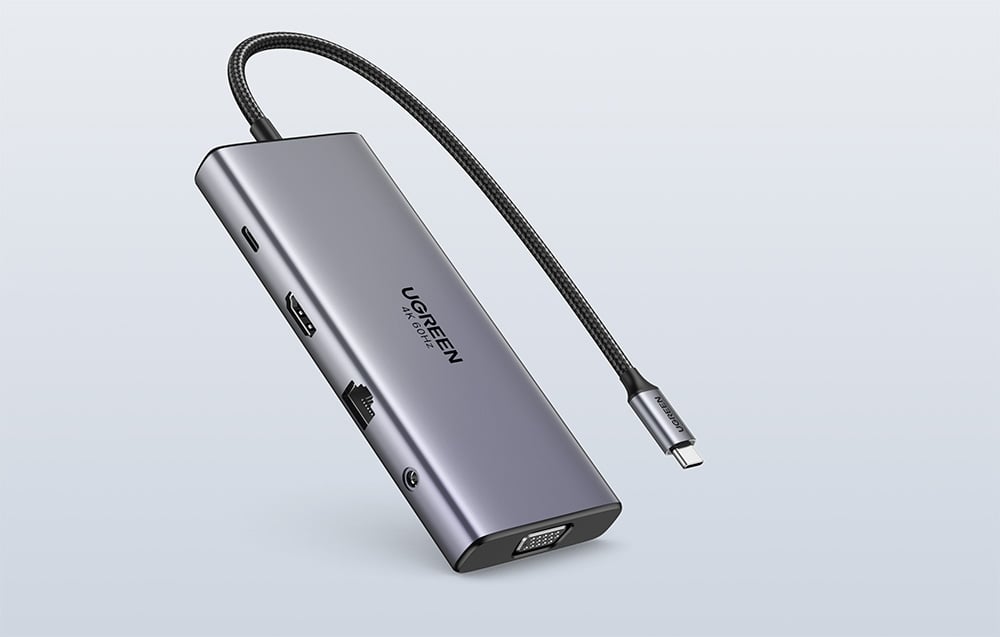 Srebrny hub ustawiony pod kątem z widocznymi portami na szarym tle